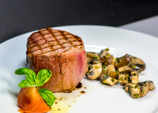 istock Roasted meat with tomatoes and mushrooms on a white plate 1066863394