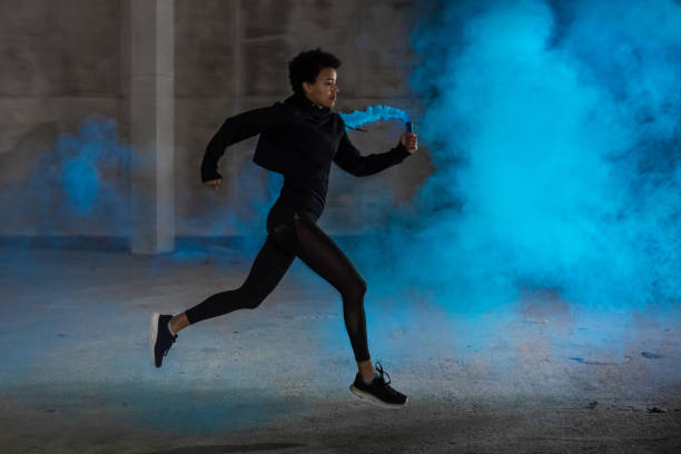 istock Young Woman Running, Holding a Blue Smoke Bomb 1066864012