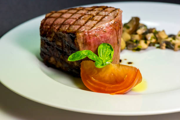 istock Roasted meat with tomatoes and mushrooms on a white plate 1066864104