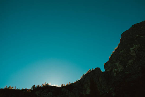 canyon haut rocher effrayant foncé au lever du jour avec le soleil derrière les arbres dans les montagnes des alpes dolomites italiennes - mountain rock sun european alps photos et images de collection