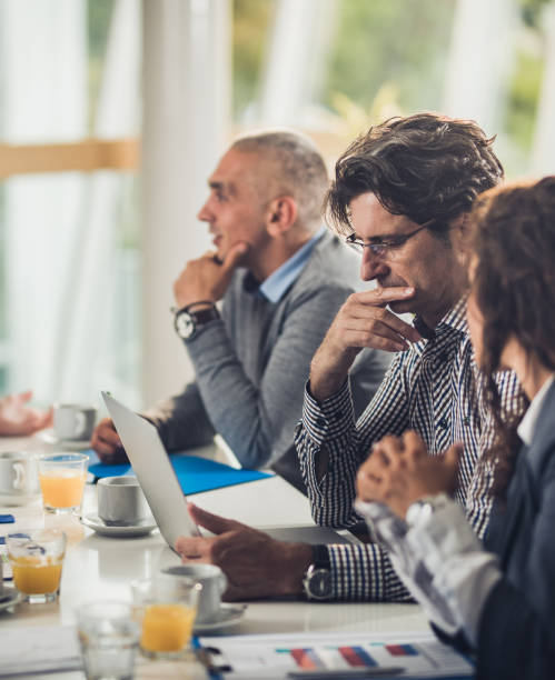 istock Pensive businessman reading an e-mail on a meeting with his colleagues. 1066871908