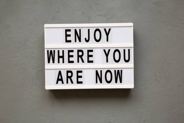 istock 'Enjoy where you are now' words on modern board over concrete background, top view. Flat lay, from above. 1066871992