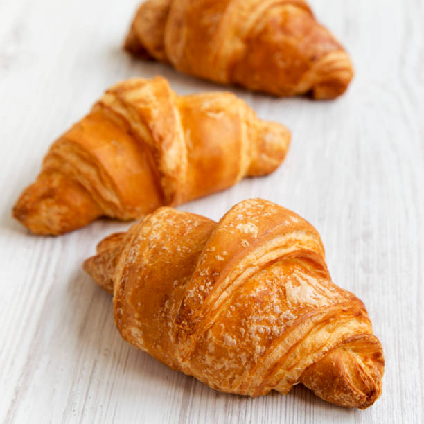 istock Fresh croissants on white wooden table, side view. Selective focus. 1066876916