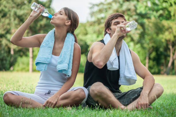 istock Young couple drinking water after exercising in nature 1066877622