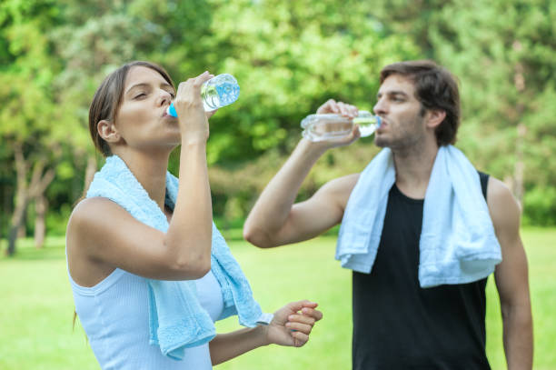 istock Young couple drinking water after exercising in nature 1066877962