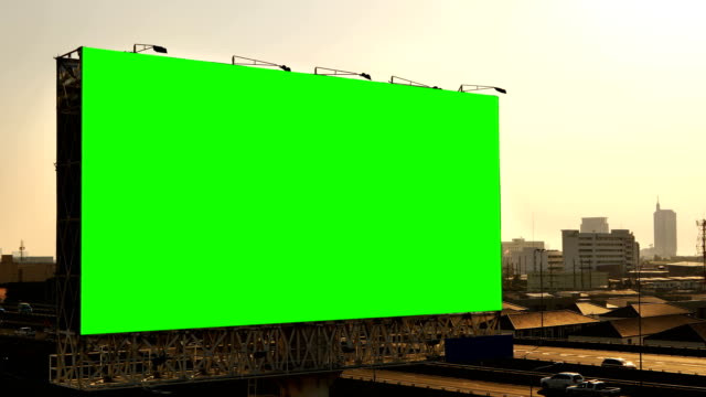 Green screen of advertising billboard on expressway during the sunset with city background in Bangkok, Thailand.
