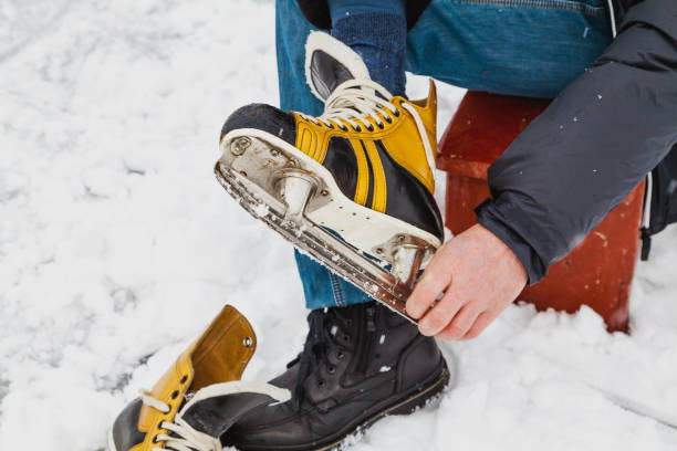 istock man takes off his skate boot from natural skating rink 1066882622