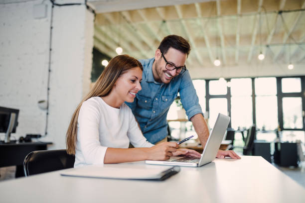 istock Two young business colleagues using a laptop and talking in a modern office. 1066891736
