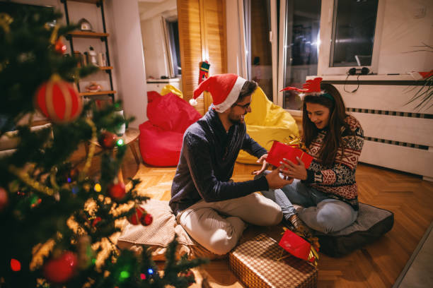 istock Couple exchanging Christmas gifts while sitting on floor. 1066892194