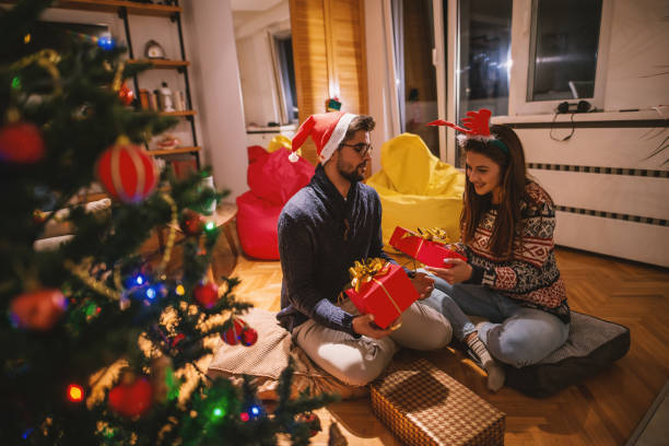 istock Couple exchanging Christmas gifts while sitting on floor. 1066894192
