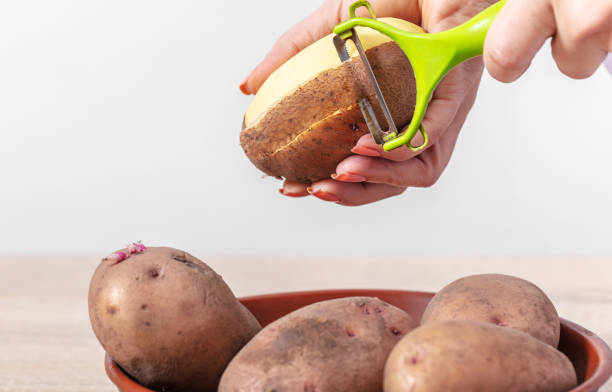 woman cook cleans potatoes - raw potato human skin peel dirty imagens e fotografias de stock