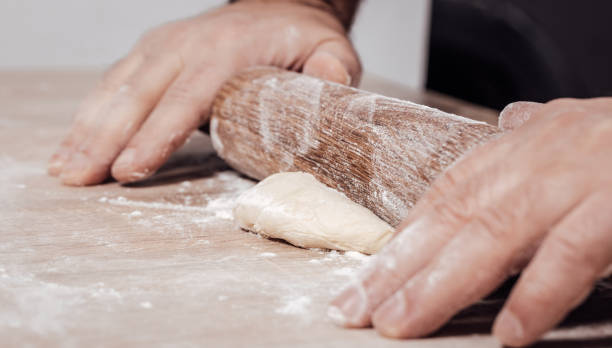 istock male cook rolls out dough with rolling pin 1066897528
