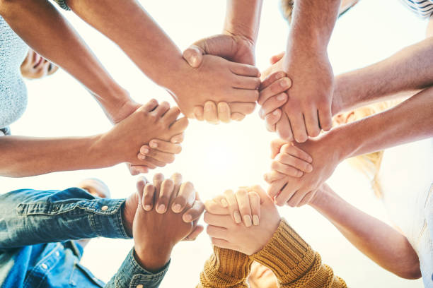 Community is considered as the cradle of humanity Closeup shot of a diverse group of people holding hands together in unity hands clasped stock pictures, royalty-free photos & images