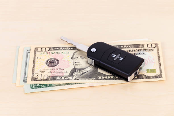 istock Modern car key and dollar banknote on white background 1066911386