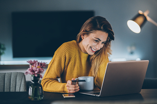 Young woman shopping online with credit card and lap top at home