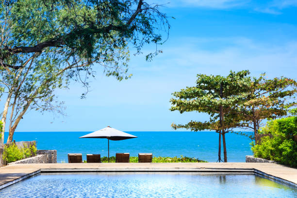 Two lounge chairs and a closed umbrella by the sea, creating a peaceful and minimal coastal relaxation scene.