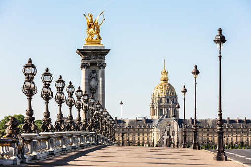 Pont Alexandre III bridge over the River Seine and the Hotel des Invalides in the background in the sunny summer morning. Bridge decorated with ornate Art Nouveau lamps and sculptures. Paris, France