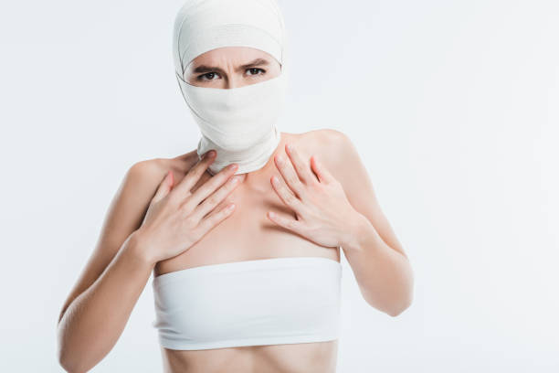 istock scared woman with white bandages over face and head isolated on white 1066921404