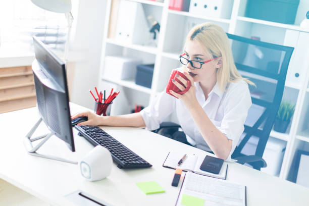 istock A young girl working at a computer in the office and holding a red Cup. 1066933156