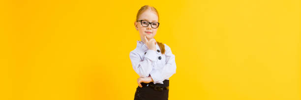 Girl with red hair on a yellow background. A charming girl in transparent glasses put a finger to her chin. Portrait of a beautiful girl in a white blouse and a brown pencil skirt. see through leggings stock pictures, royalty-free photos & images