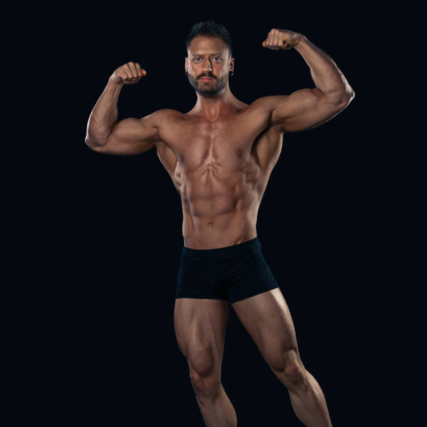 istock Brutal strong bodybuilder athletic man posing on black background. 1066939028
