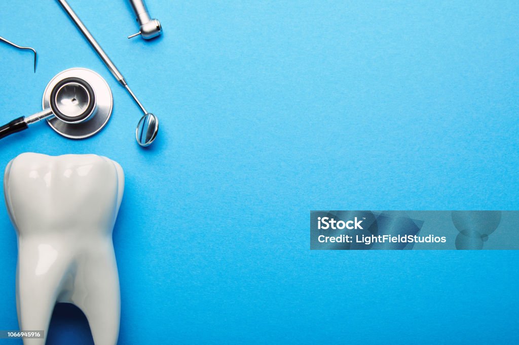 flat lay with tooth model, stethoscope and sterile dental instruments arranged on blue backdrop Dental Health Stock Photo