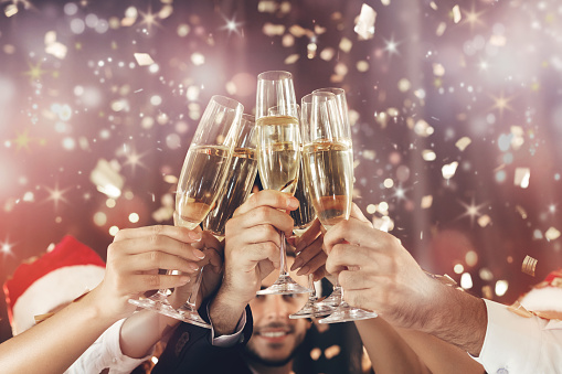 Cheers. New Year celebration. People holding glasses of champagne and making toast, holiday sparkling background