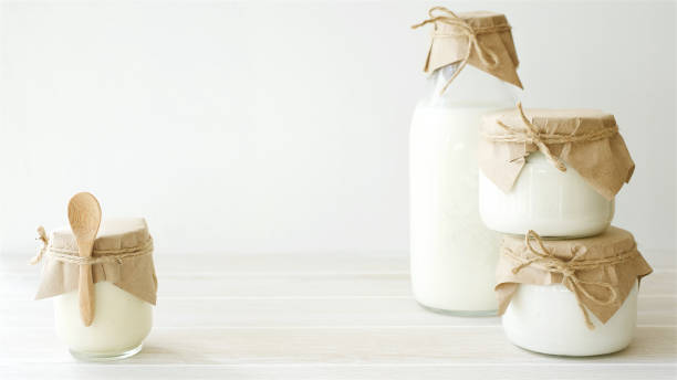 Dairy products in glass jars on light background