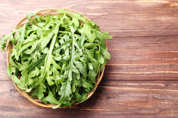 istock Green arugula leafs in basket on brown wooden table 1066954176