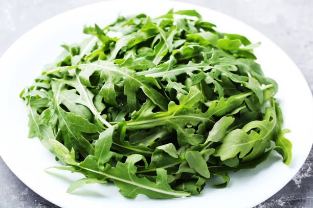 istock Green arugula leafs in plate on gray wooden table 1066954594