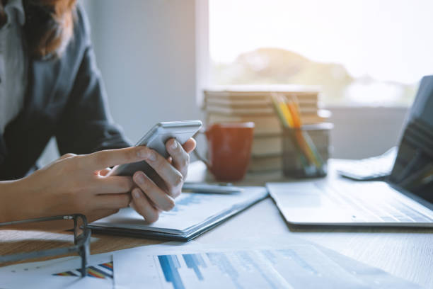 istock business women working using smart mobile phone and laptop with finance graph at office workplace desk. business technology concept. 1066955588
