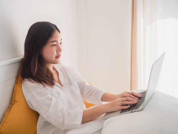 istock Young asian woman using computer in bedroom 1066955996