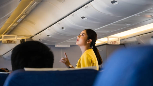 weibliche flight attendant unterstützt einen passagier in der economy class die strecke bangkok - tokyo nok scoot airline. - scoot stock-fotos und bilder