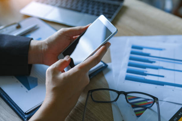 istock Closeup view of business women working using smart mobile phone for checking text message with finance graph at table. business technology concept. 1066959524