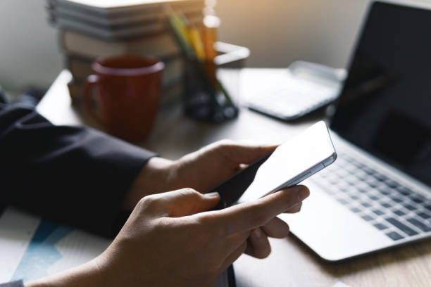 istock Closeup view of business women working using smart mobile phone for checking text message with finance graph at table. business technology concept. 1066959616