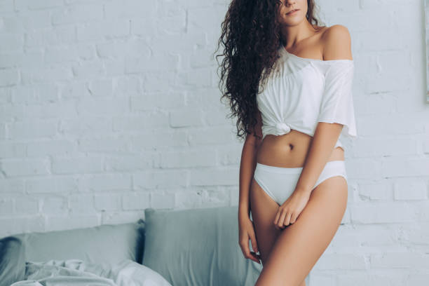 vue partielle de la séduisante femme bouclée en slip blanc dans la chambre à la maison - underwear photos et images de collection