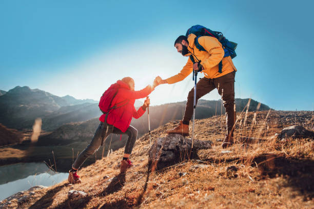 Helping hand - hiker woman getting help on hike happy overcoming obstacle.