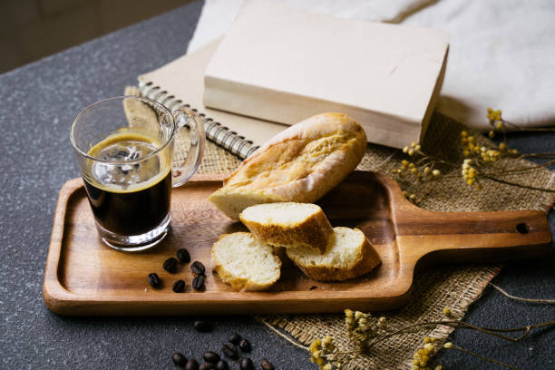 istock A coffee, bread, wood plate and book setting on black background 1066961134