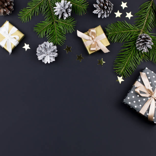 istock Festive Christmas background with fir branches, presents, decorations on black, copy space 1066963250