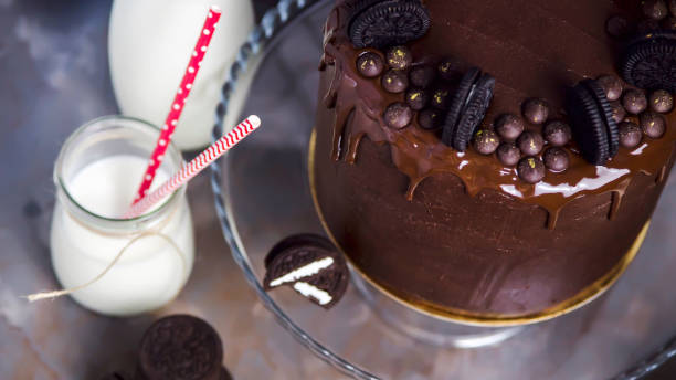 istock Chocolate cake decorated with biscuits next to jars of milk with tubules and broken biscuits. Banner image Top view 1066965522