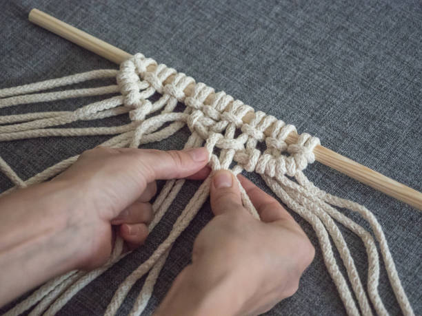 istock Macrame. Girl weaves macrame. White thread, female hand, grey background, close-up 1066968942