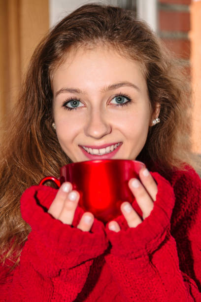 istock Woman in red holding cup with beverage and smiles 1066976876