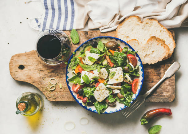 insalata tradizionale greca con formaggio feta e bicchiere di vino - greek culture salad olive feta cheese foto e immagini stock