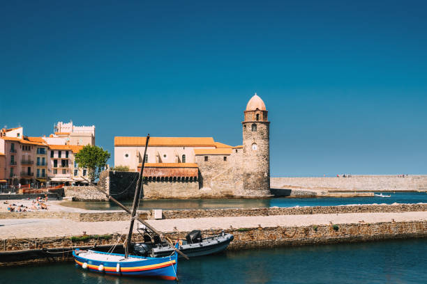 Collioure, France. Boats Moored On Berth Near The Church Of Our Lady Of The Angels Across Bay In Sunny Spring Day Collioure, France. Boats Moored On Berth Near The Church Of Our Lady Of The Angels Across Bay In Sunny Spring Day. collioure stock pictures, royalty-free photos & images