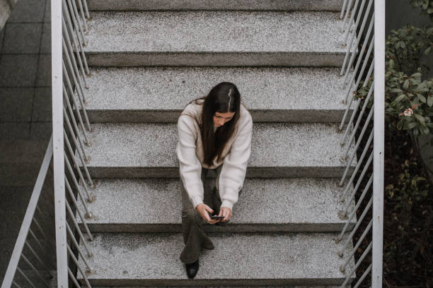 istock Young woman with smartphone sitting on staircase 1066983746