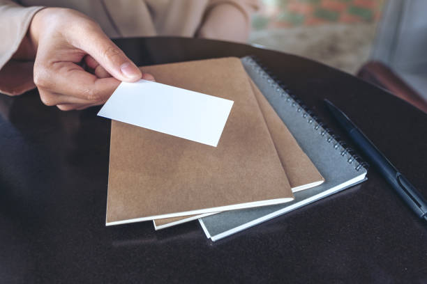 istock A businessman's hand holding and giving empty business card with notebooks on table 1066986346