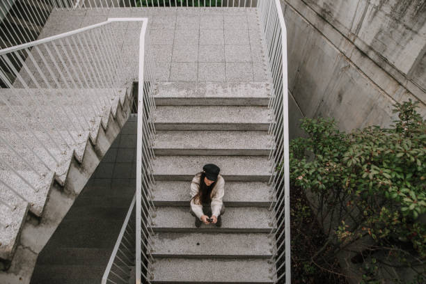 istock Young woman with smartphone sitting on staircase 1066989894