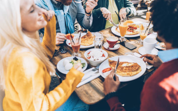 grupo étnico multi de amigos comiendo el almuerzo en un restaurante - brunch fotografías e imágenes de stock