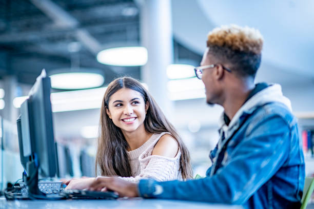 istock Two university students smiling and talking in the library 1066992334