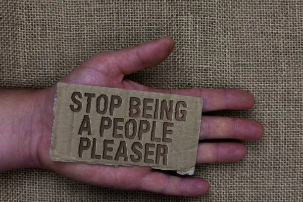 Photo of Conceptual hand writing showing Stop Being A People Pleaser. Business photo text Do what you like not things other people want Cardboard with marked some letters on human hand jute sack ground.